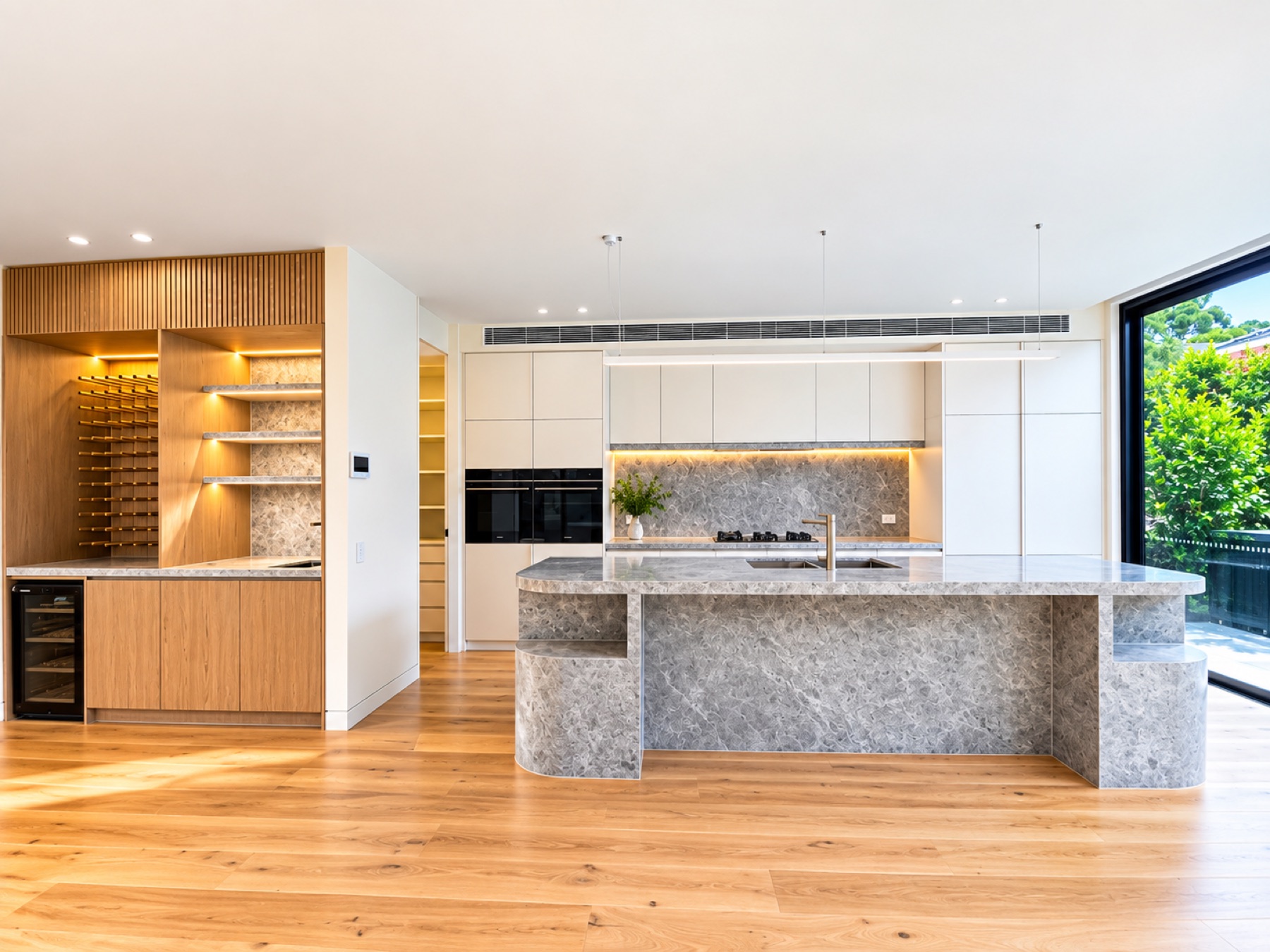Bright custom kitchen with stone island and timber wine storage